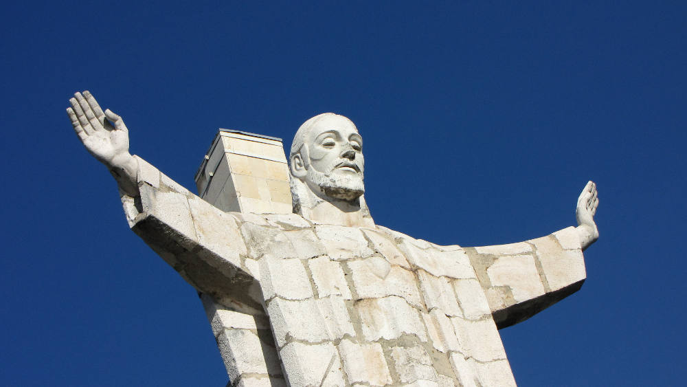 foto de primer plano del monumento. Se ve la cabeza de un Cristo con los brazos abiertos simbolizando un abrazo.