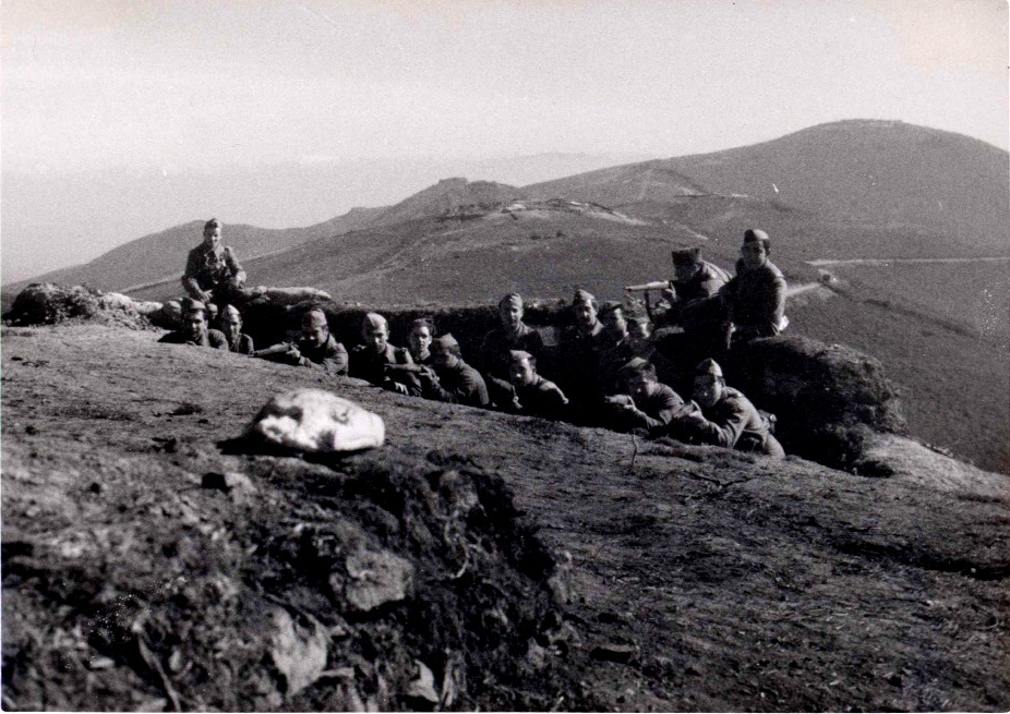 foto en la que 15 soldados están en una trinchera apuntando con sus armas.