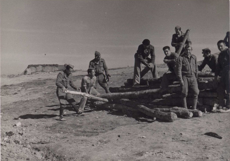 foto en la que se ven a 10 soldados moviendo postes de madera aplicando el efecto palanca.