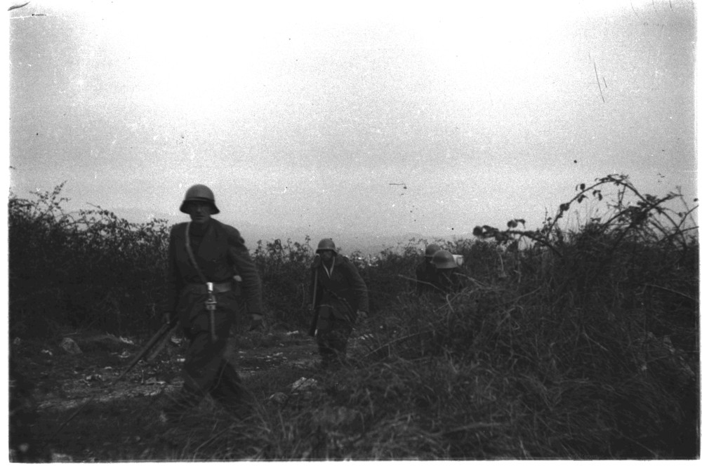 foto de 4 milicianos armados subiendo al monte Naranco. El que está en primer plano camina normal, el resto semiagachados.