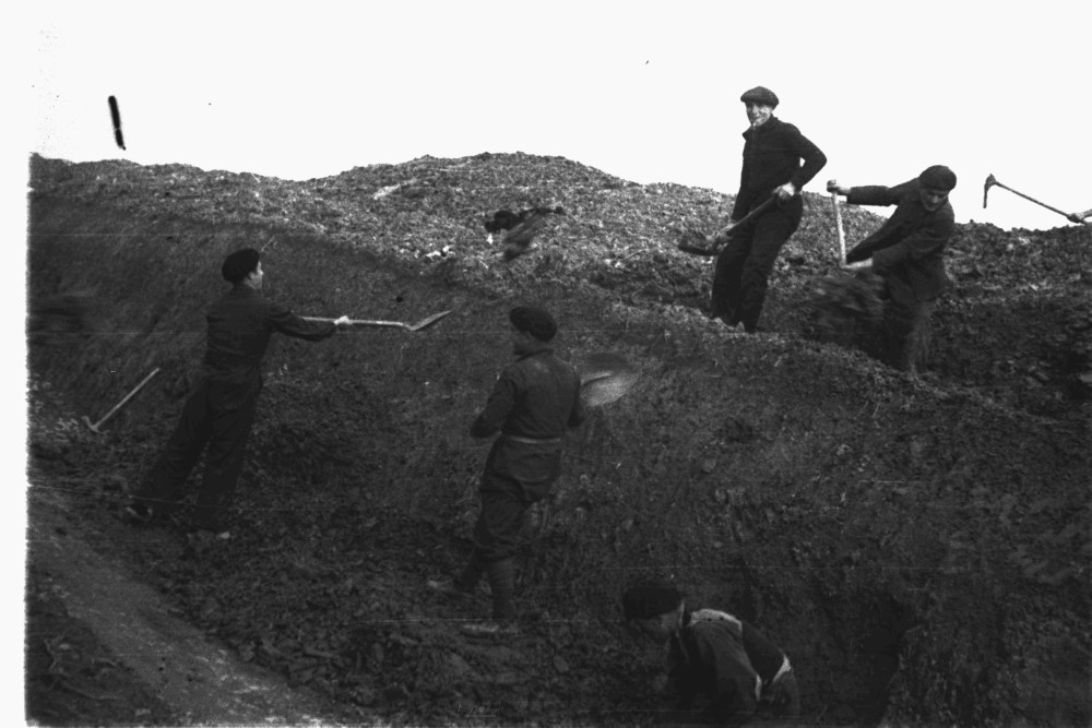 foto de milicianos cavando una trinchera con palas. 3 de ellos están en una fila y otros 2 en otra fila a un poco más sobreelevada.