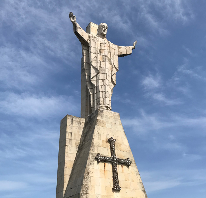 foto del monumento de piedra dedicado al Sagrado Corazón. Un Cristo sobre un pedestal tiene sus brazos extendidos sobre la ciudad de Oviedo