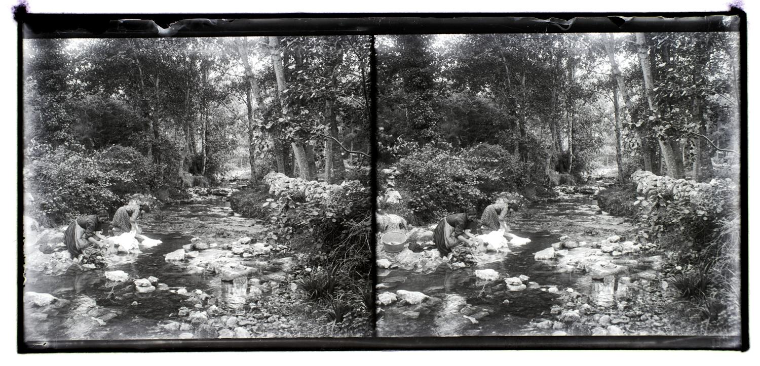 Fotografía de dos mujeres lavando la ropa en una poza de un rio.