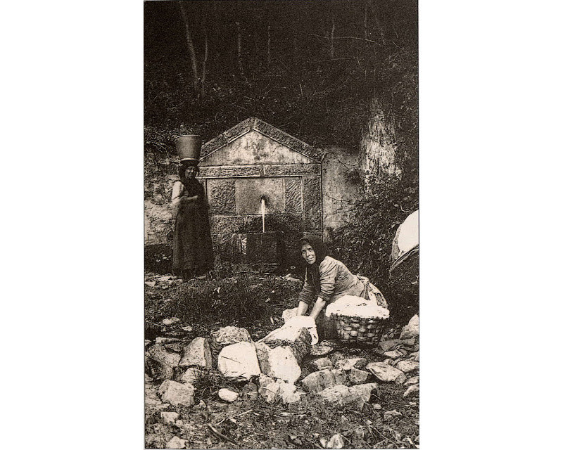 foto de dos mujeres delante de una fuente lavando ropa