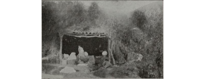 foto de espaldas de una mujer lavando en un lavadero muy rústico.