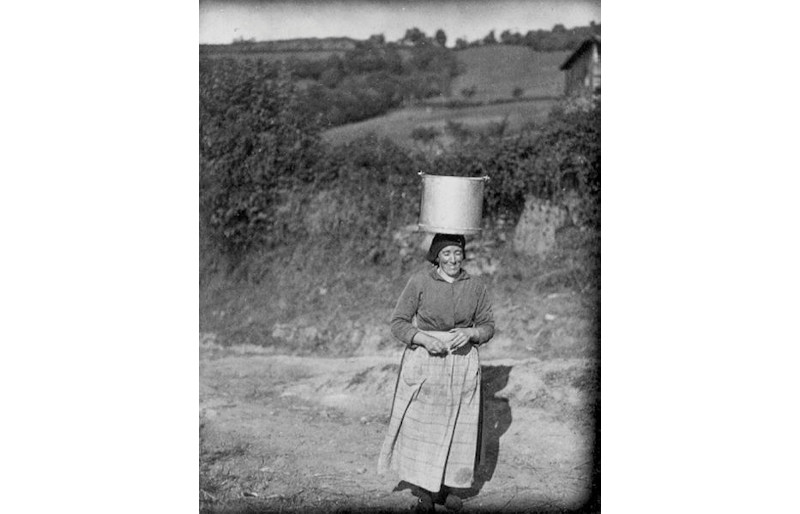 foto de una mujer llevando un caldero con agua sobre la cabeza