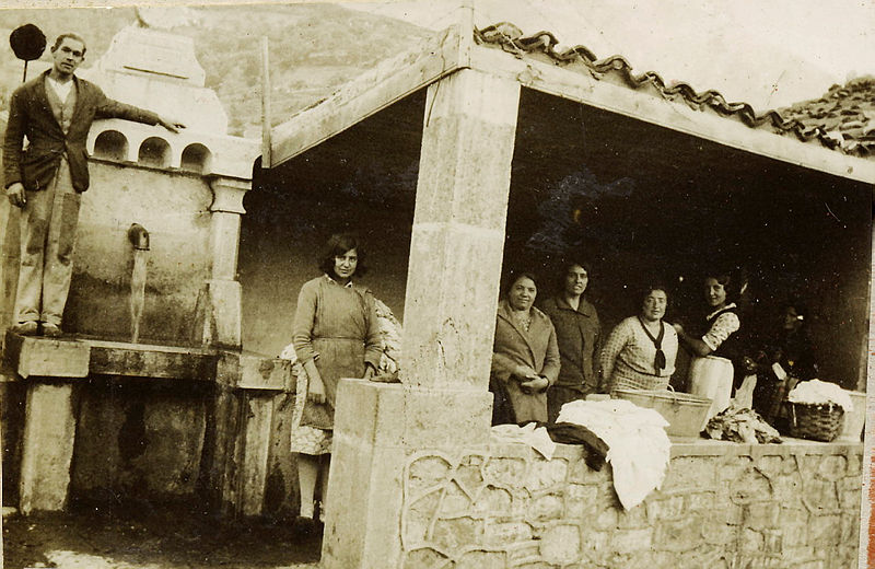 foto de 6 mujeres posando en un lavadero con techo. Un hombre está subido encima de una fuente junto al lavadero.
