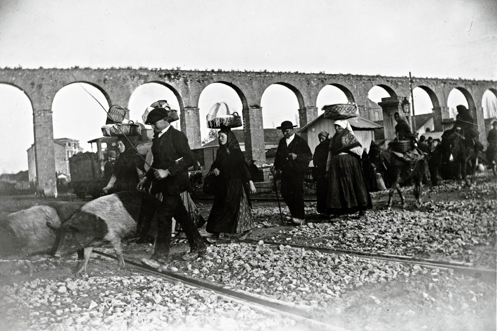 foto del acueducto con mujeres pasando mercancias en cestos en la cabeza y hombres conduciendo animales