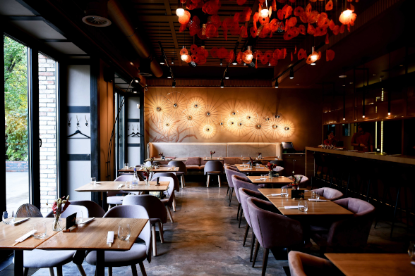 foto del interior de un restaurante con mesas y sillas. En la parte izquierda se ven las puertas abiertas que dan a la terraza del restaurante.